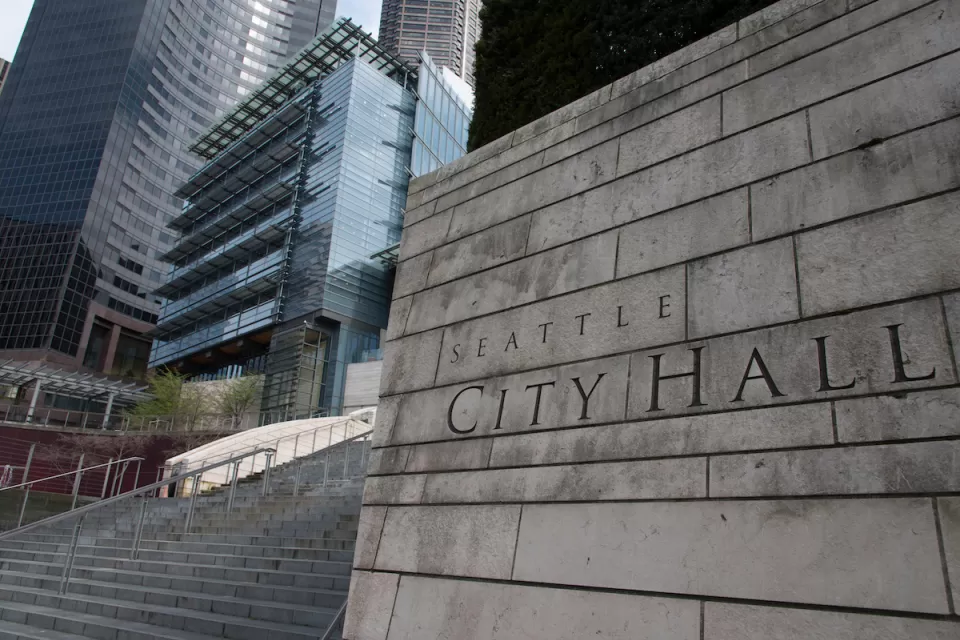 Close-up of carved Seattle City Hall title on front of concrete buildin next to staircase.